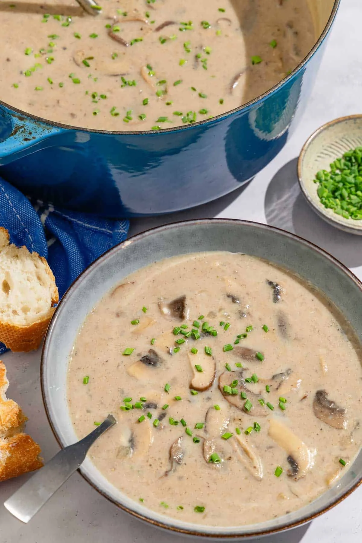 Bowl of creamy mushroom soup garnished with herbs and served with crusty bread