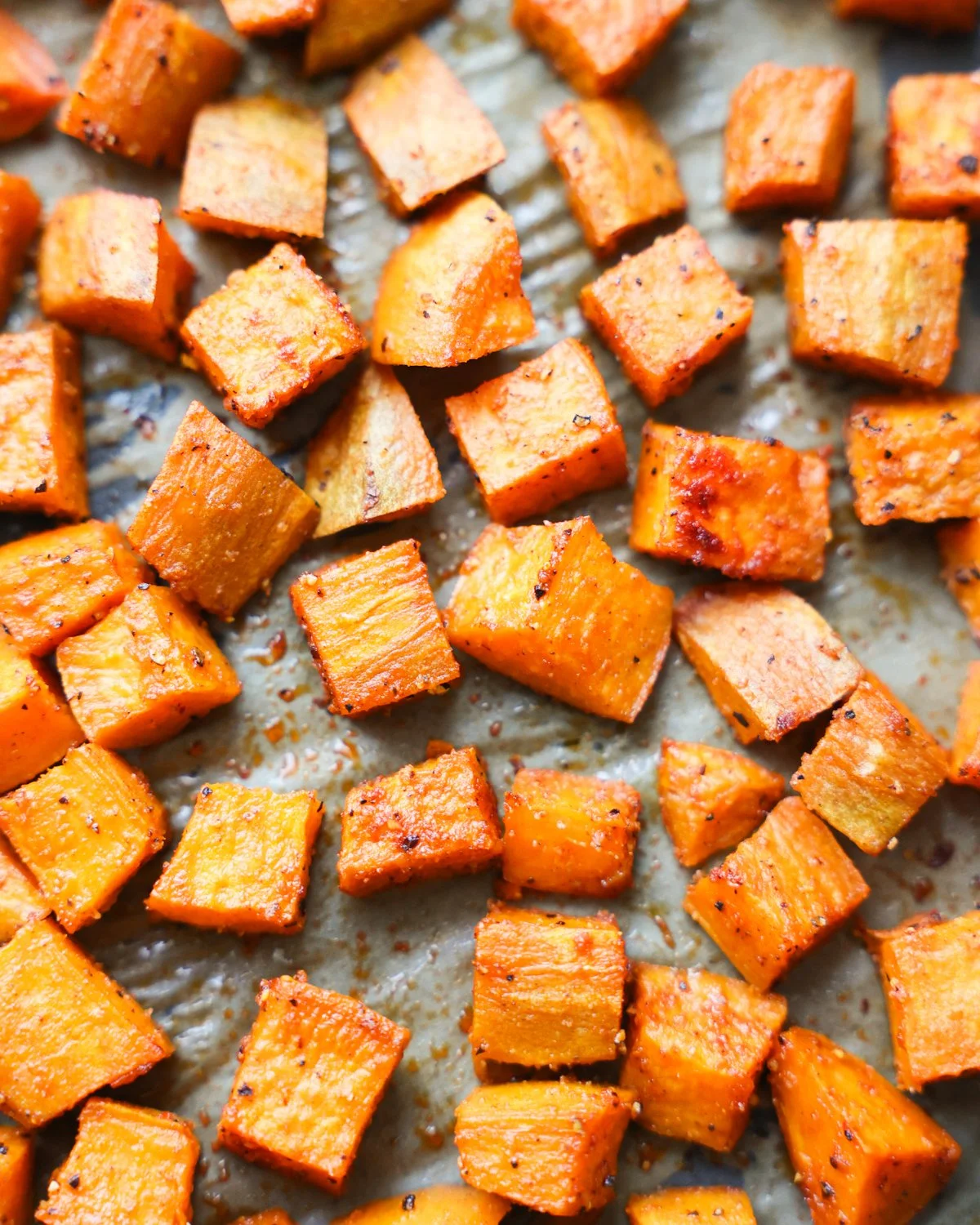 Bowl of perfectly roasted sweet potatoes garnished with herbs