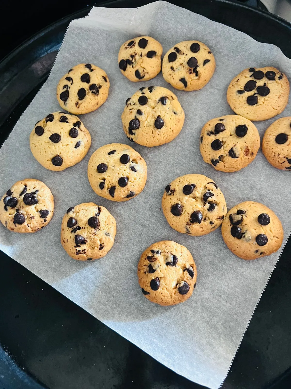 Soft and chewy chocolate chip cookies with golden edges on parchment paper