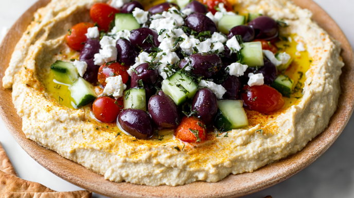 Creamy Mediterranean hummus dip topped with olive oil, chickpeas, paprika, and fresh herbs