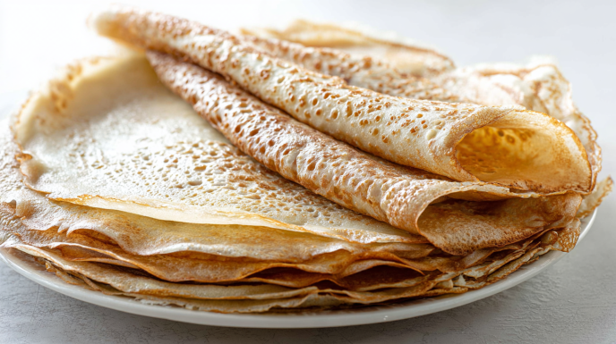 Thin sourdough crepes folded and topped with fresh berries and powdered sugar