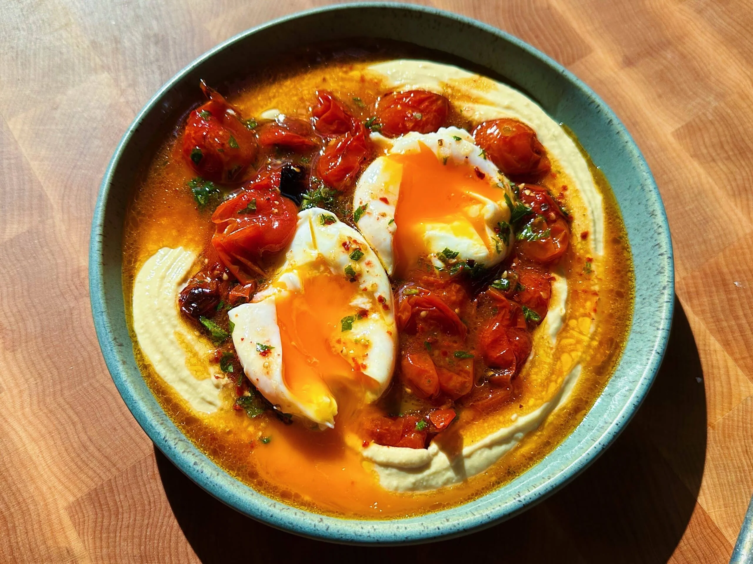 Poached eggs served with roasted tomatoes and hummus on a plate