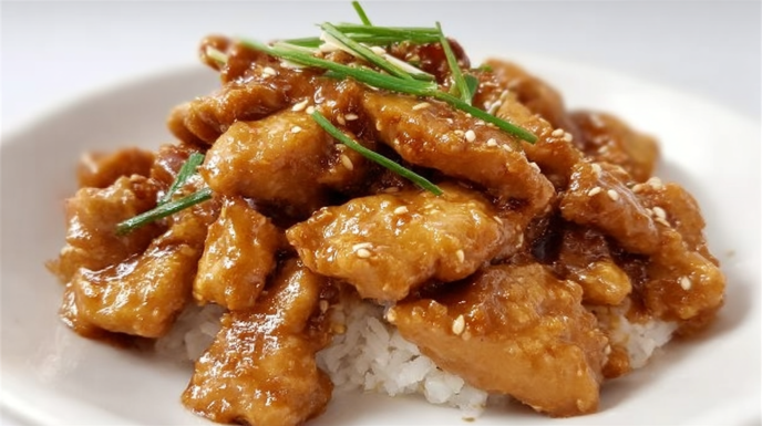 Chinese peanut butter chicken with crispy chicken pieces coated in a creamy peanut sauce and garnished with sesame seeds