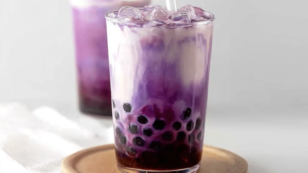Purple boba tea with tapioca pearls, creamy milk tea, and vibrant purple color in a clear glass